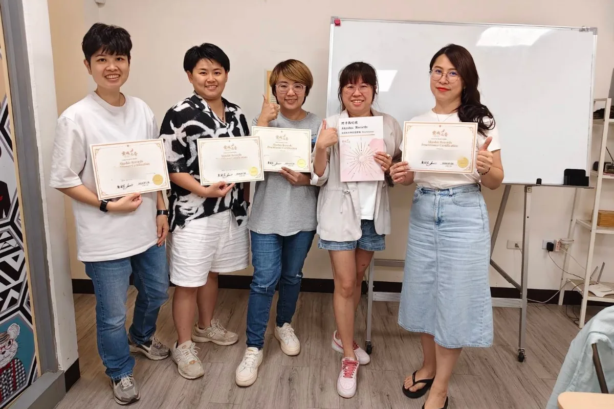 五位學員在教室白板前合影，四人手持「Akashic Records Practitioner Certification」結業證書，一人拿著阿卡西紀錄講義，多人笑著比讚；證書上的姓名已模糊處理。